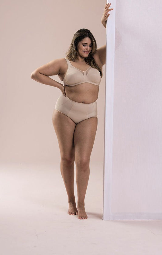 A woman wearing a beige, wire-free, wire-free bra with seamed cups.