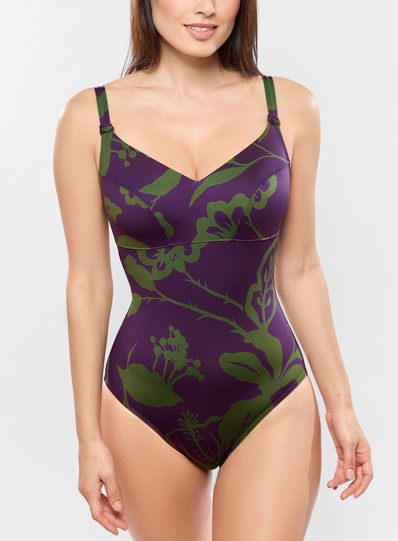 Purple swimsuit with green floral pattern worn by a model on a white background