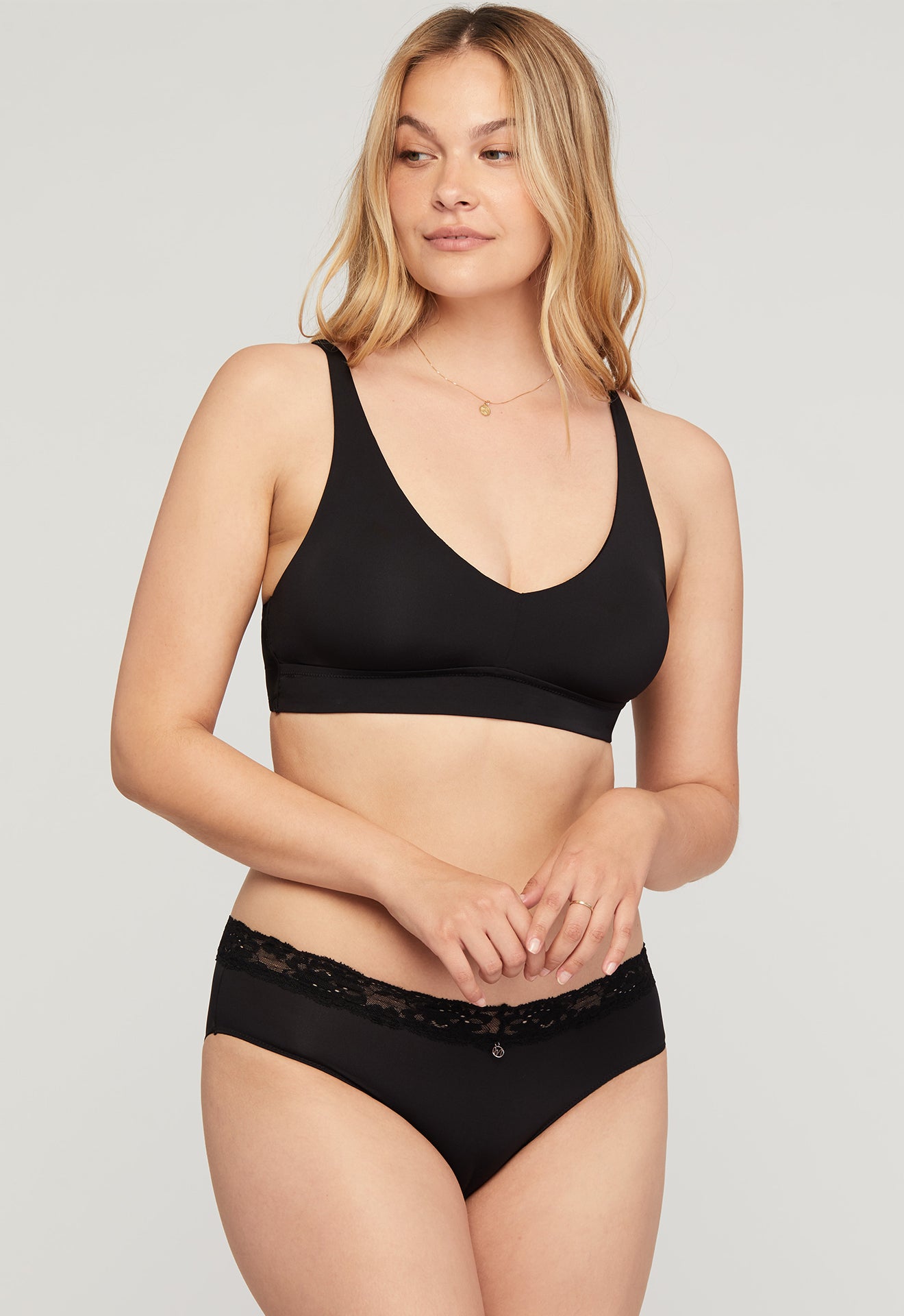 Woman wearing a black bra and underwear set on a plain background