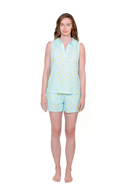 Woman wearing sleeveless aqua polo and matching lemon print shorts with a white background